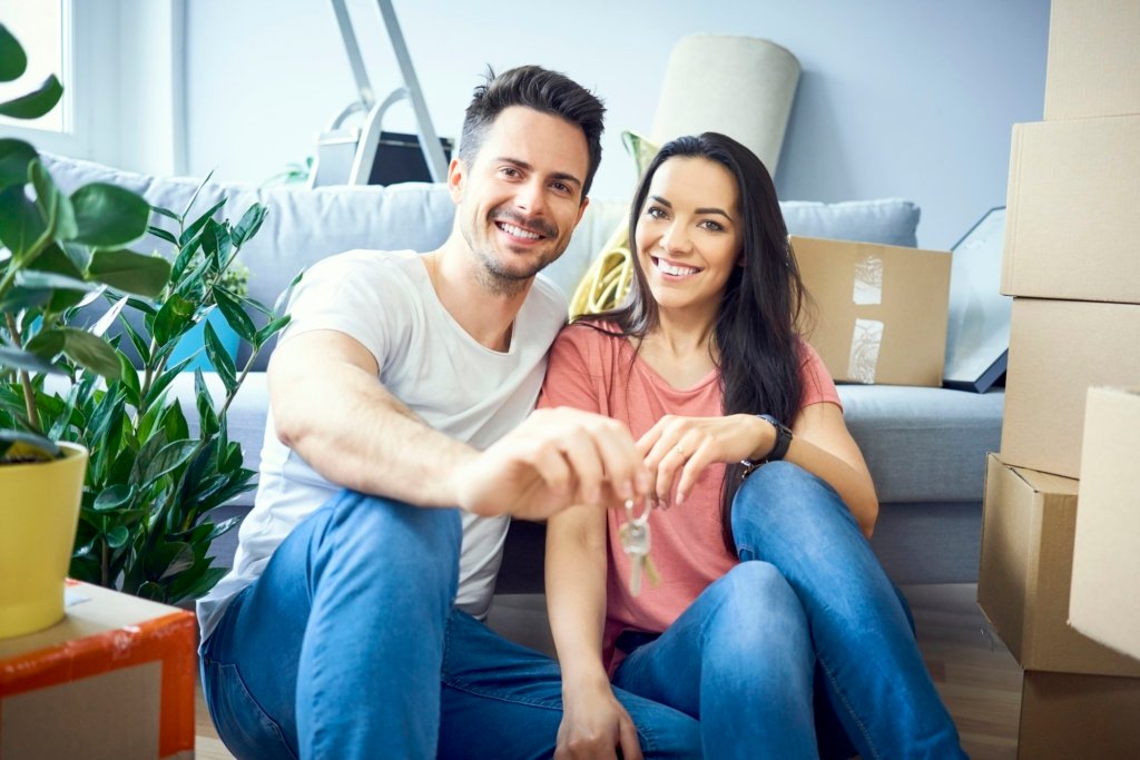 Portrait of happy couple moving in showing keys to new apartment