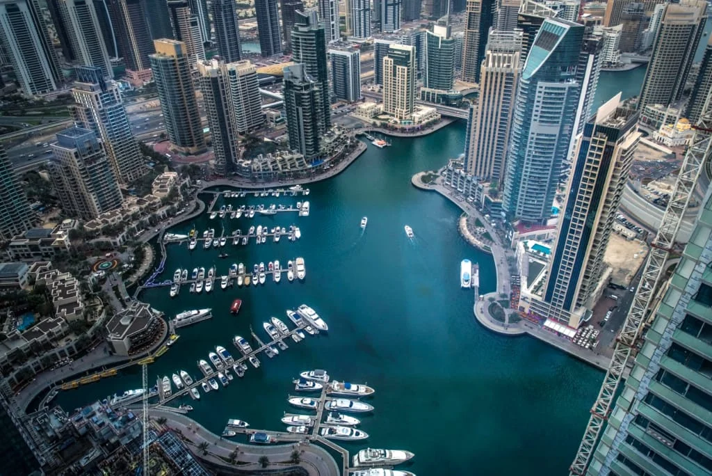 Vue urbaine de Dubaï Marina en pleine journée, avec ses tours modernes en bord de canal, ses yachts luxueux et sa promenade animée. Quartier emblématique de Dubaï, symbole d’un mode de vie haut de gamme et cosmopolite.