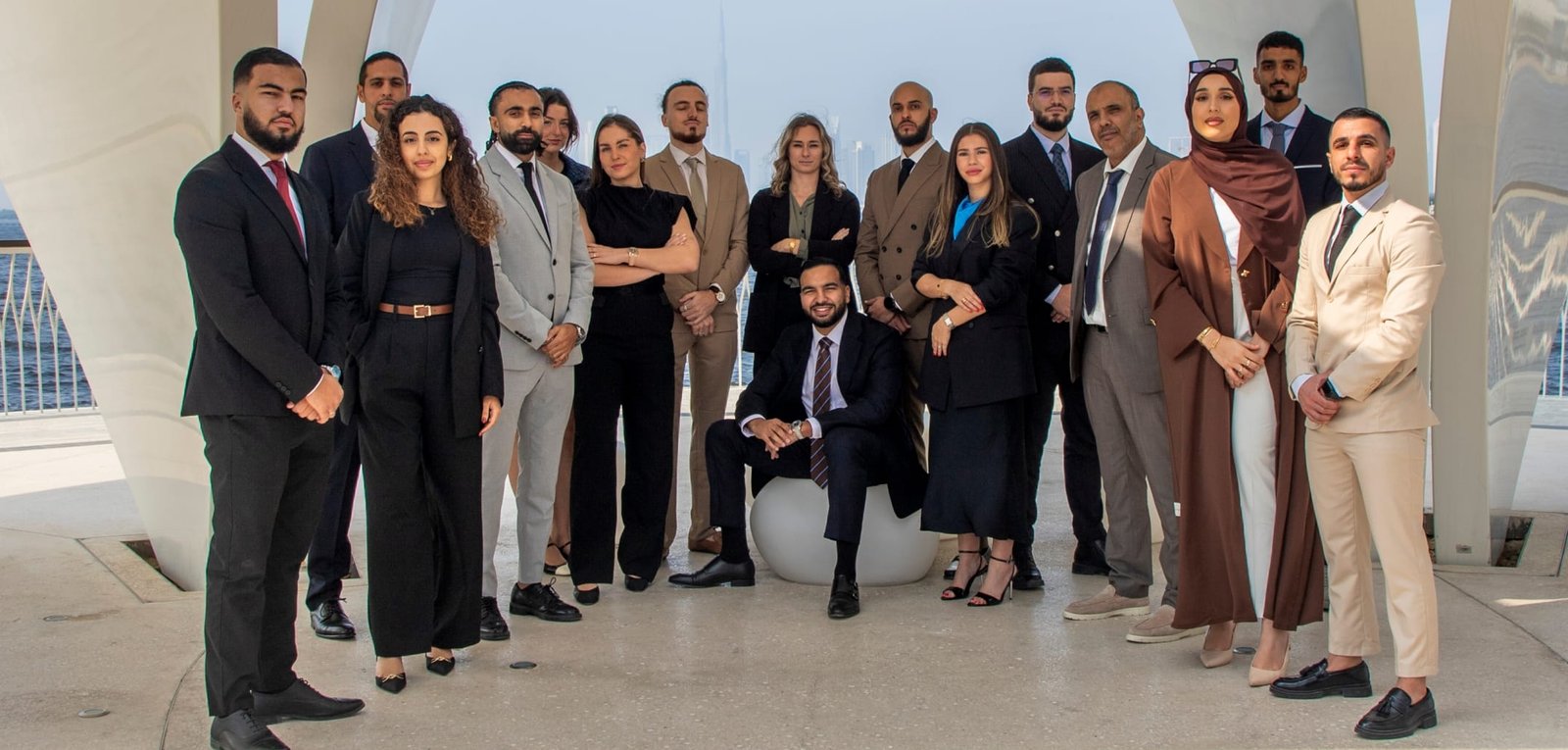 Photo de dix agents immobiliers posant en arc de cercle, vêtus avec élégance, dans un cadre lumineux sous un ciel bleu éclatant. Photo d'équipe La Riviera Real Estate - Agence immobilière française à Dubaï
