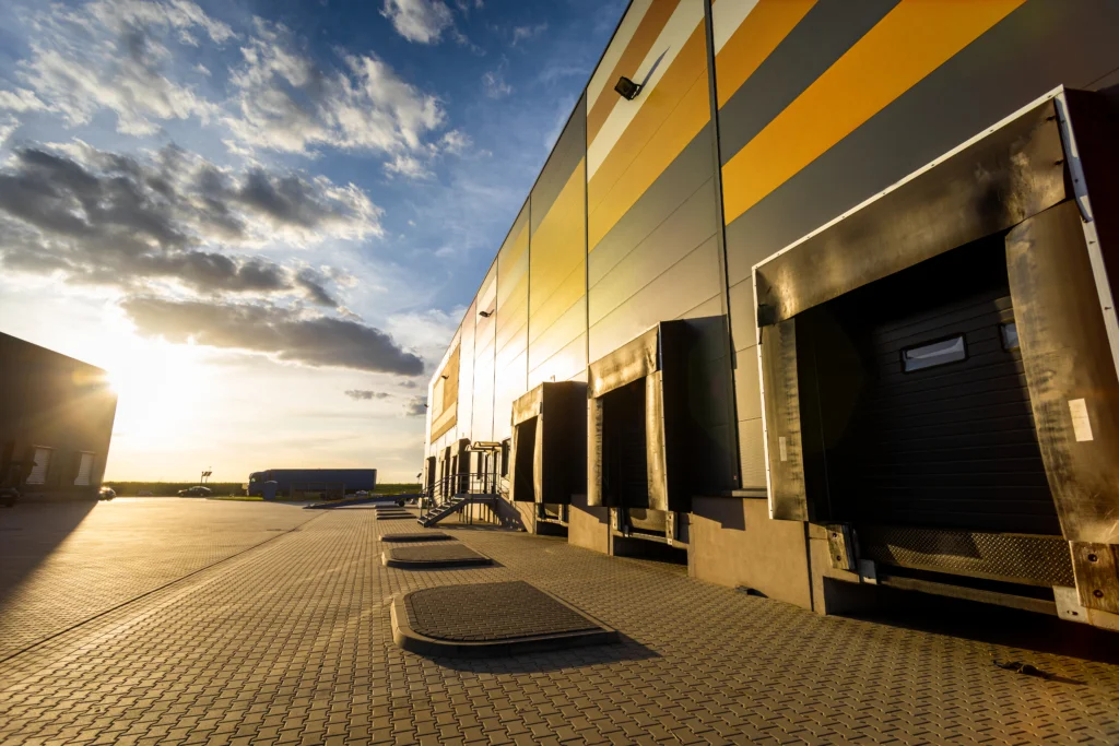 Portes de quai de chargement d’un grand entrepôt logistique, conçues pour accueillir des camions de transport de marchandises. Infrastructure industrielle moderne dédiée à la distribution, au stockage et à la gestion des flux de cargaisons.