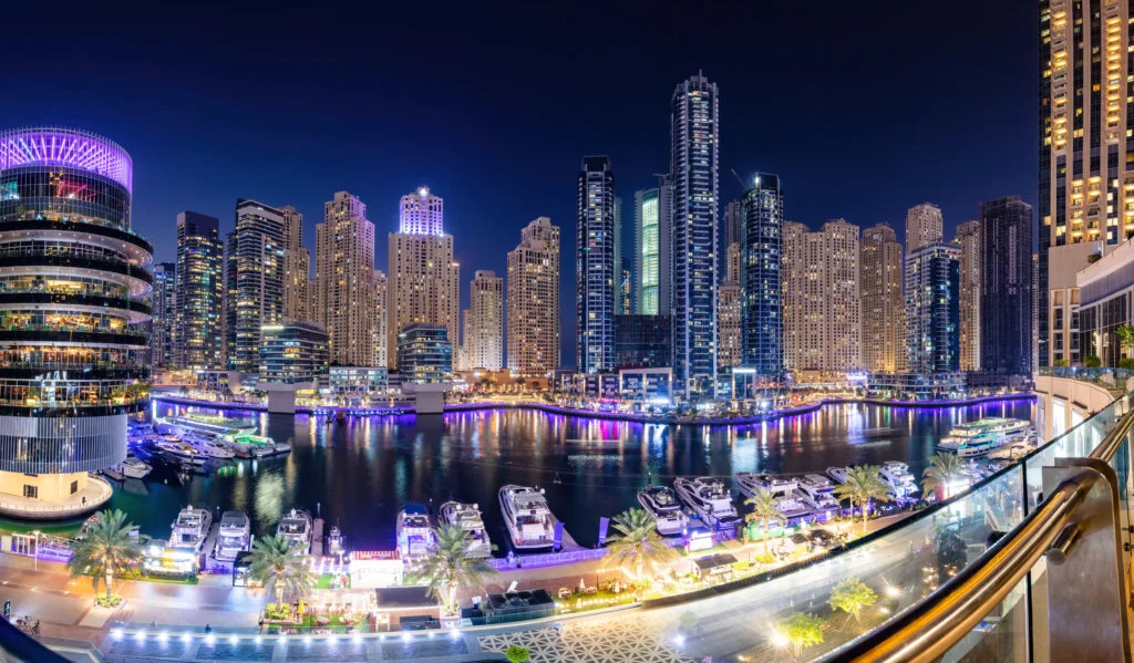 ue nocturne de la promenade de Dubaï Marina, illuminée par les lumières des gratte-ciel et les reflets sur l’eau. Ce quartier animé incarne le luxe urbain avec ses restaurants, boutiques et yachts amarrés le long du canal.